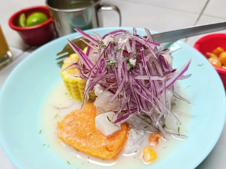 Peruvian ceviche topped with red onion, served with sweet potato and corn