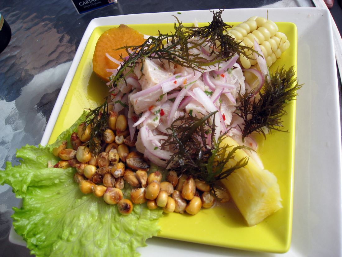 Fish ceviche with onions, toasted corn kernels and lettuce on a yellow plate